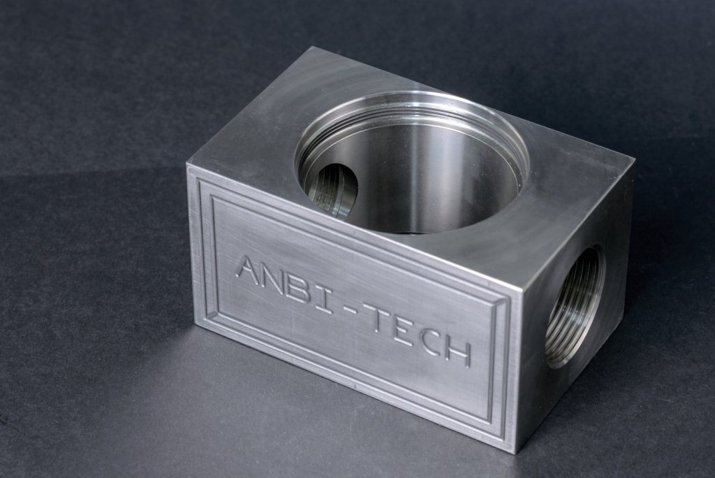 Milled 316L stainless steel block with ANBI-TECH engraving and a threaded through hole