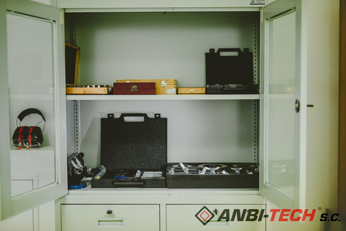 An open steel workshop cabinet filled with measuring tools, micrometer sets and boxes.