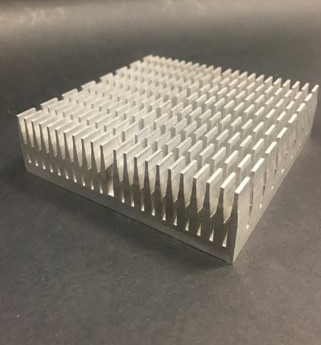 Square metal cooling heat sink with a dense array of vertical fins lying on a dark surface.