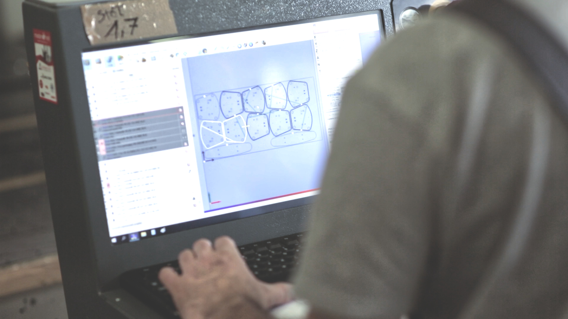 Operator using a CNC machine control station with the part nesting layout visible on the computer screen.