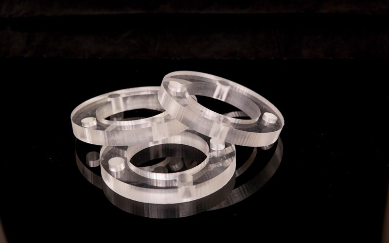 Three transparent plastic rings with pins, arranged on a black reflective surface.