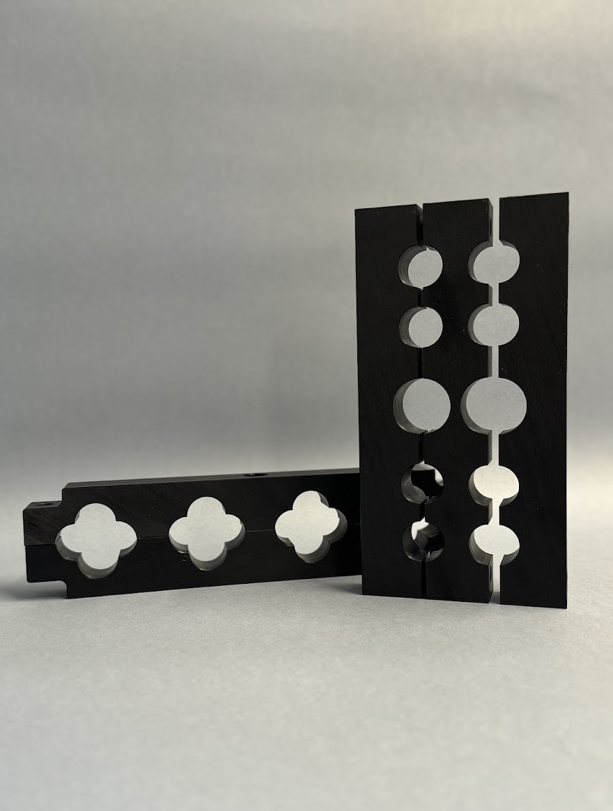 Black split plastic mounting blocks with profiled clamping holes on a grey background.