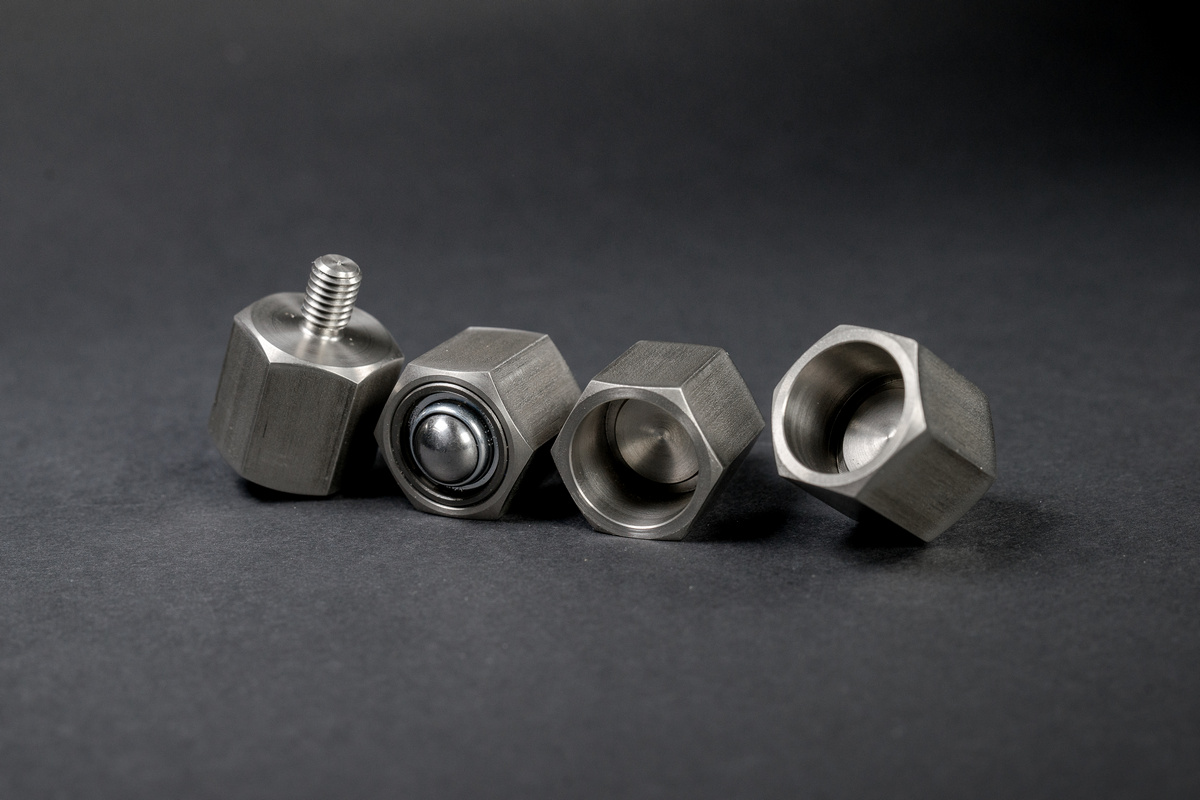 Four silver, brushed metal components with a hexagonal shape arranged in a row on a dark background.
