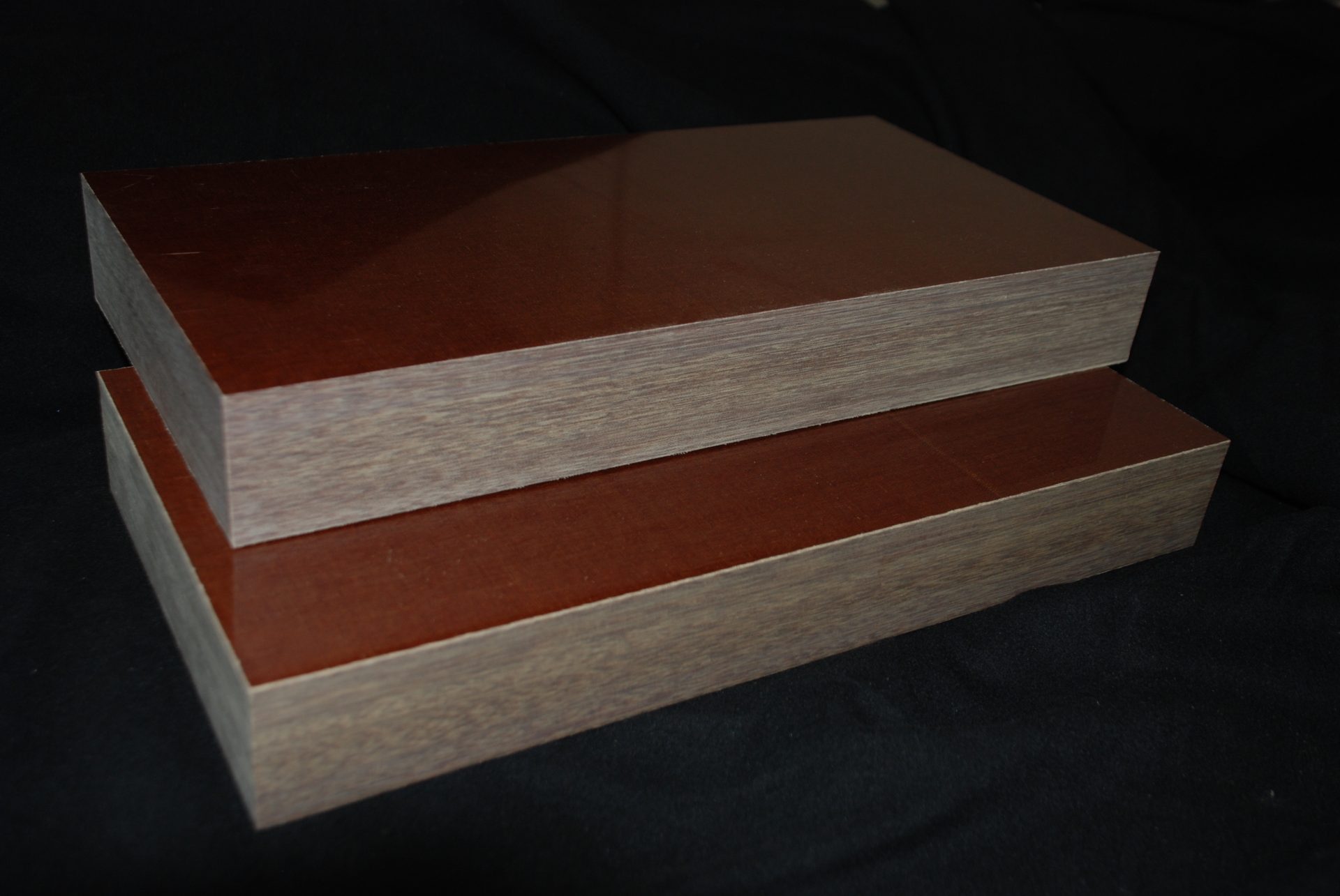 Two brown rectangular blocks with glossy, ridged surfaces lying on a dark black surface.