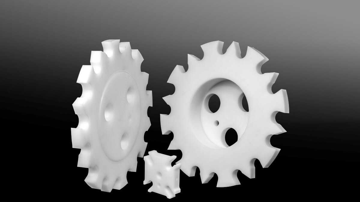 Three white machine components with cut-outs and holes, of different sizes, placed on a dark studio background.