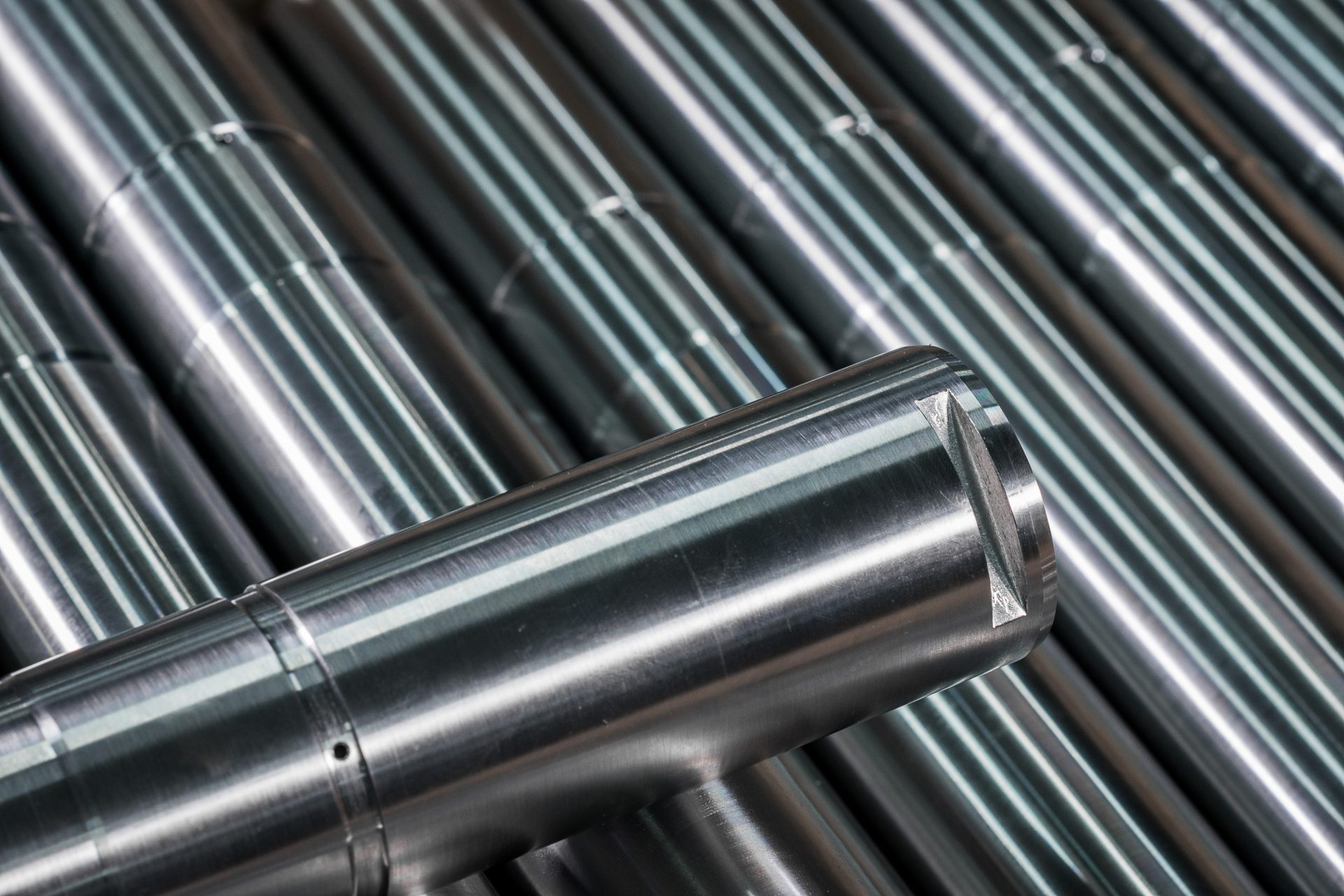 Metal rollers with smooth, shiny surfaces arranged parallel to one another at a workstation.