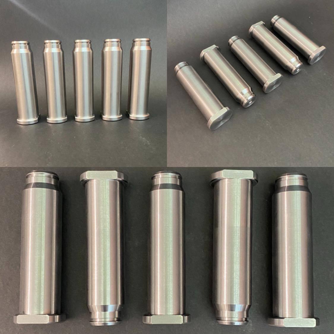 Five cylindrical silver metal components with smooth surfaces lying at even intervals on a black background.