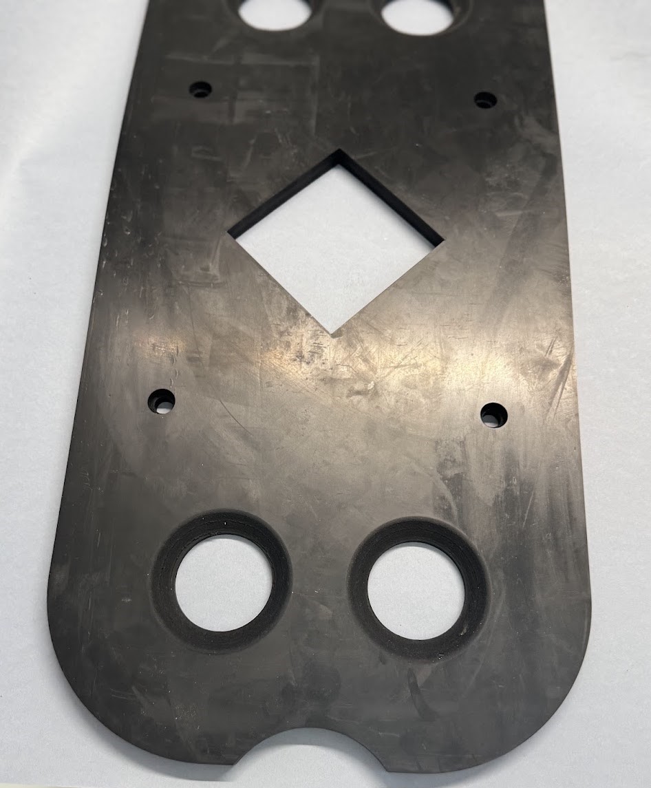 A flat black technical plate with a central diamond-shaped cut-out and round holes against a light background.