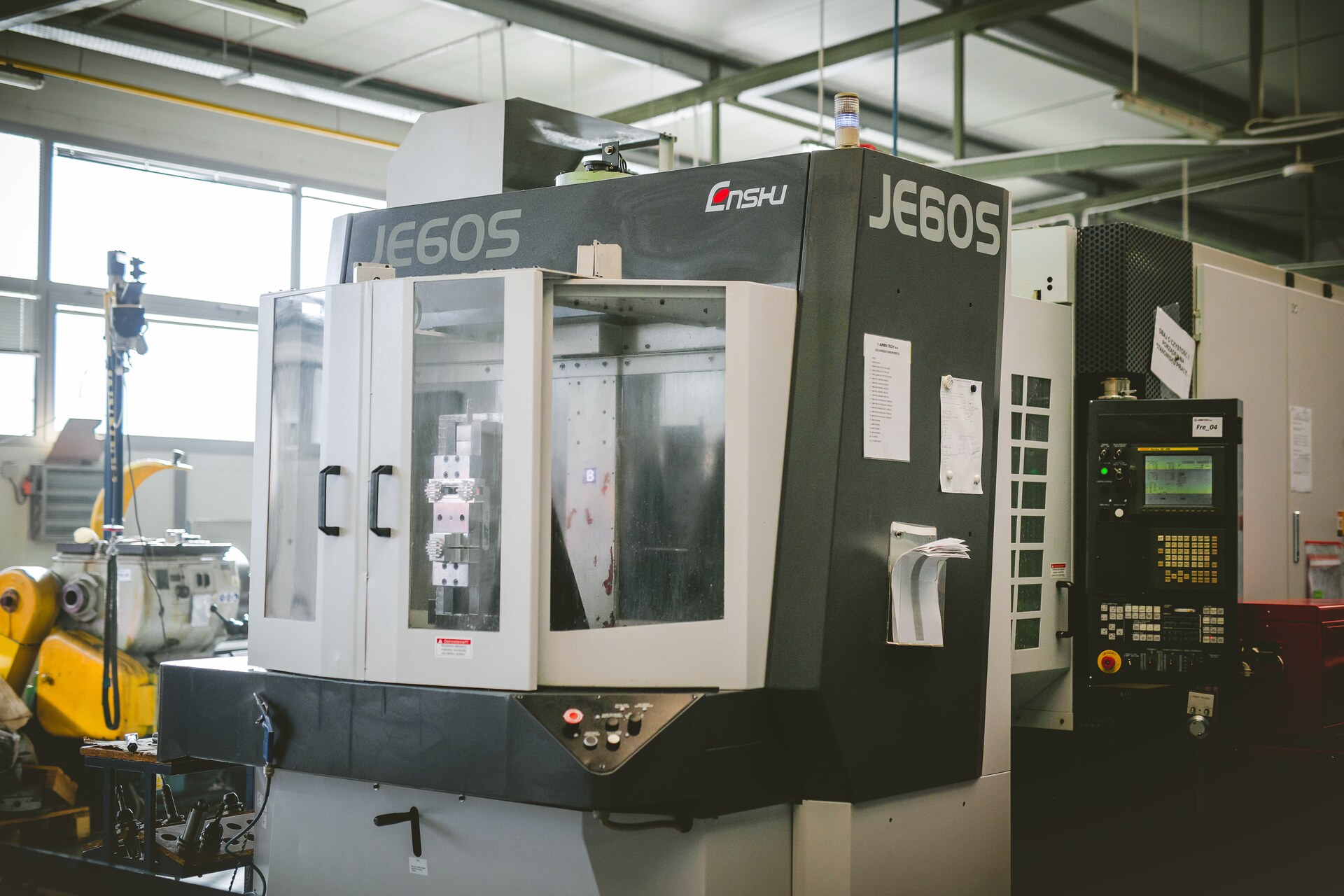 ENSHU JE60S horizontal machining centre in the hall, two vices with parts inside a glazed enclosure, control panel alongside.