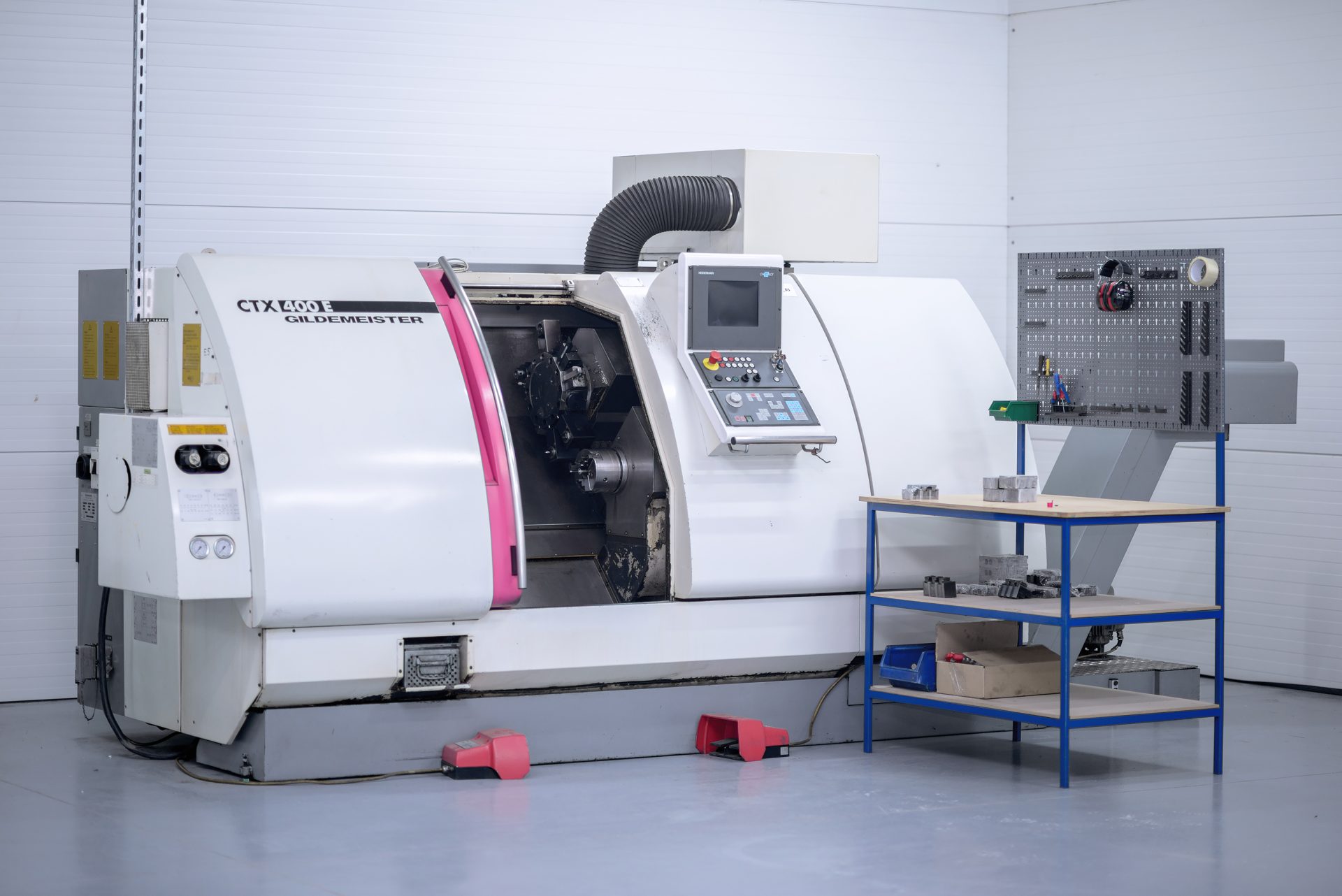 Industrial CNC lathe with an open enclosure, control panel and tool rack in the production hall.